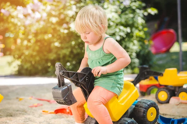 Дитина катається на іграшковому тракторі на дитячому майданчику — стокове фото