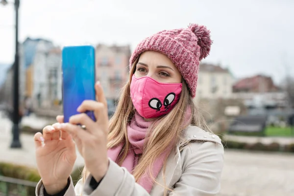 Kvinne med koronamaske som lager selfie med telefon – stockfoto