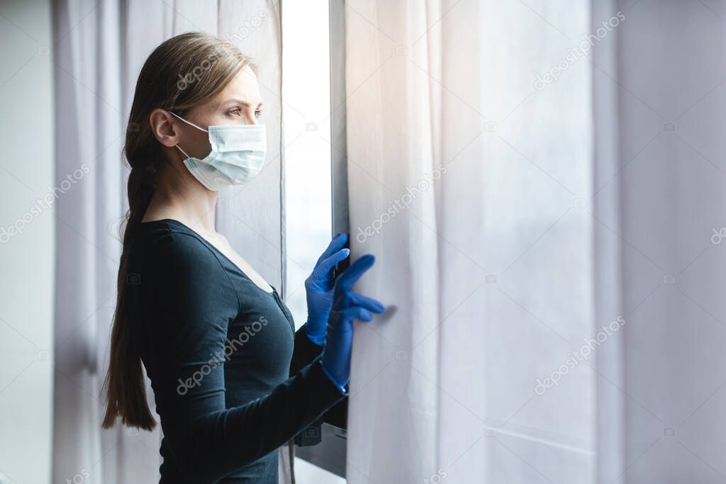 Bored woman in corona quarantine looking out of window