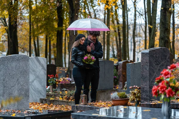 Man och kvinna på en kyrkogård med blommor — Stockfoto