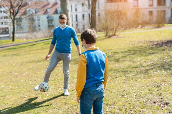 Tata i syn grali w piłkę nożną w parku podczas kryzysu koronawirusowego — Zdjęcie stockowe