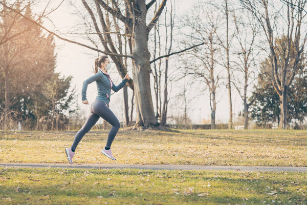 Fit woman running during health crisis with face mask
