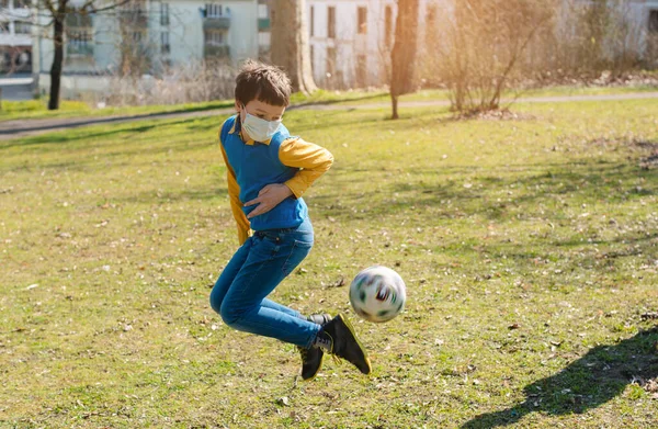 Menino jogando futebol no parque, apesar da crise de Covid-19 — Fotografia de Stock