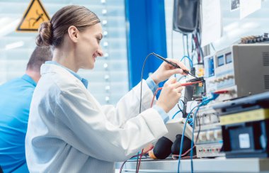Mühendislerden oluşan bir ekip laboratuarda bir elektronik ürünü test ediyor ve ölçüyorlar.