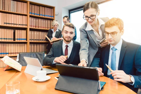 Avvocati nel loro studio legale che lavorano su computer con libri in background — Foto Stock