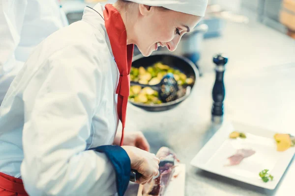Chef cook in fancy restaurant kitchen slicing ham for a dish — Stock Photo, Image