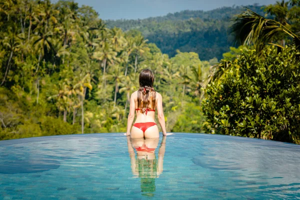Donna in piscina tropicale guardando la giungla — Foto Stock