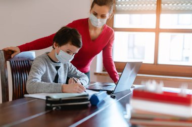 Anne ve çocuk kriz sırasında öğretmenleriyle e-öğrenim seansı yapıyorlar.