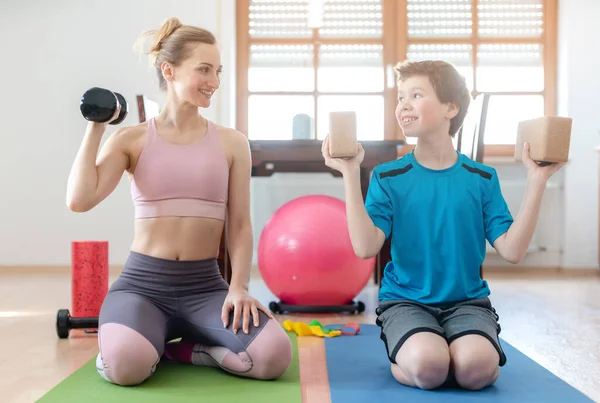 Madre e hijo haciendo entrenamiento con pesas en casa durante el toque de queda de cierre — Foto de Stock