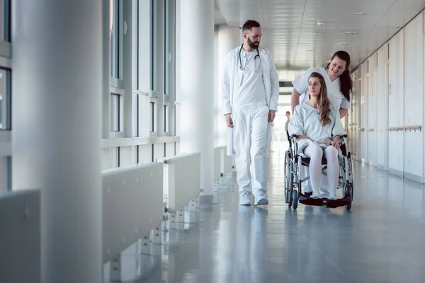 Lekarz, pielęgniarka i pacjent na wózku inwalidzkim w korytarzu szpitalnym — Zdjęcie stockowe