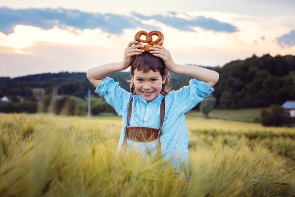 Jovem menino bávaro com pretzel no prado — Fotografia de Stock