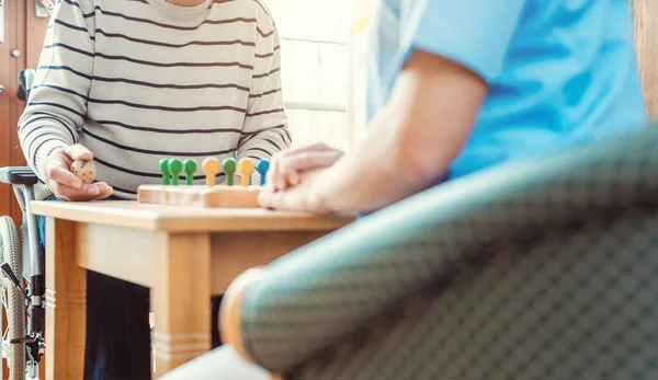 Nurse and senior in retirement home playing a board game — Stock Photo, Image