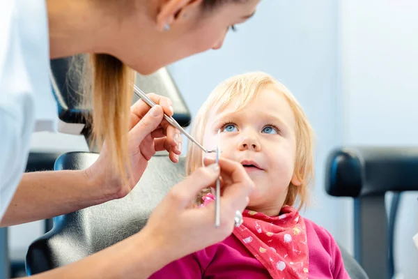 Dentista explicando o tratamento para uma criança usando um brinquedo de pelúcia — Fotografia de Stock