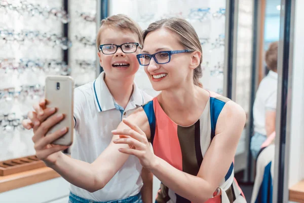 Madre e hijo tomando selfie con gafas nuevas en la tienda de optometría —  Fotos de Stock