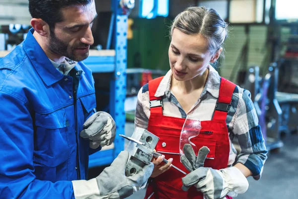 金属加工品の測定値を確認する女性と男性の労働者 — ストック写真