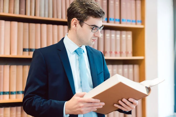 Advogado em seu escritório lendo precedentes em livros grossos — Fotografia de Stock