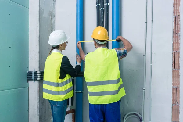 Bauarbeiter messen Rohre auf Baustelle — Stockfoto