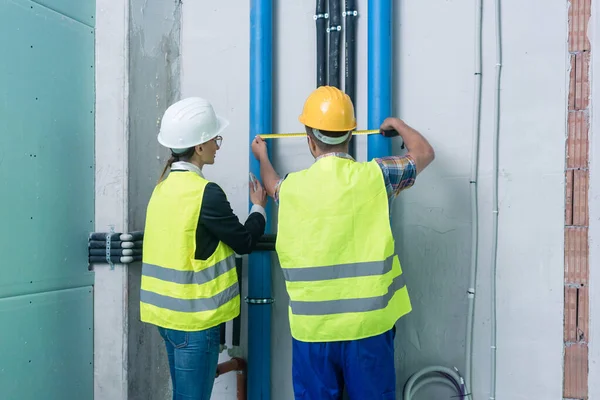 Construction workers measuring pipes on site — Stock Photo, Image