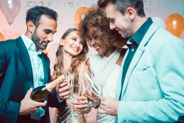 Pessoas de festa em um clube celebrando o ano novo derramando champanhe — Fotografia de Stock