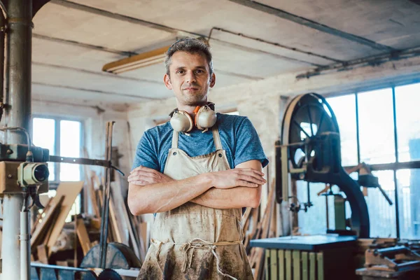 Carpenter standing in his wood workshop looking at camera — Stock Photo, Image