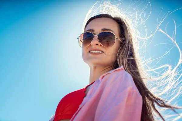 Kvinna i badkläder bakgrundsbelyst mot en blå himmel — Stockfoto