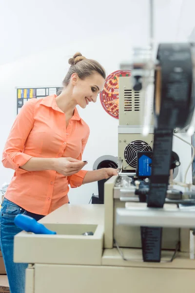İşçi baskı makinesinden yeni çıkmış tekstil etiketini kontrol ediyor — Stok fotoğraf