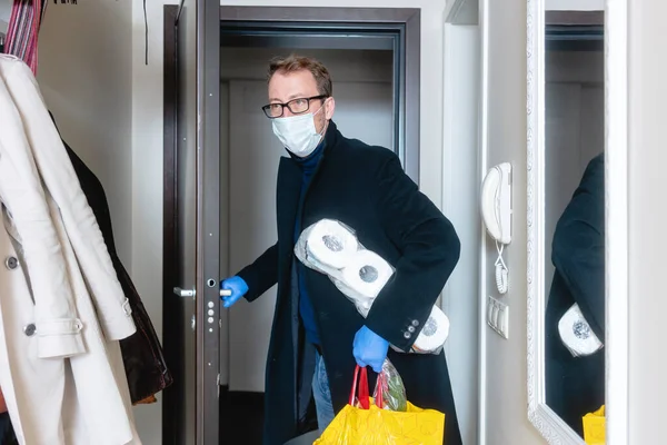 Hombre con máscara médica llegando a casa de compras y acaparamiento — Foto de Stock