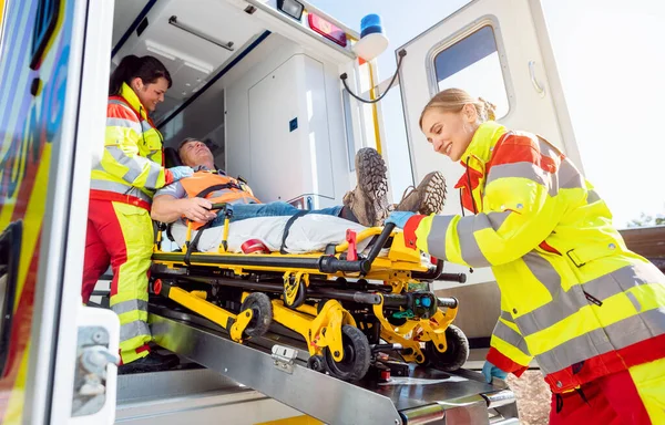 Paramédicos colocando o homem ferido na maca em carro de ambulância — Fotografia de Stock