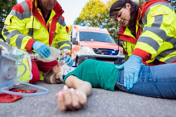 Médico de emergência ventilando mulher ferida após acidente de moto — Fotografia de Stock