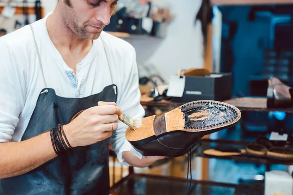 Shoemaker putting glue on sole of a shoe — Stock Photo, Image