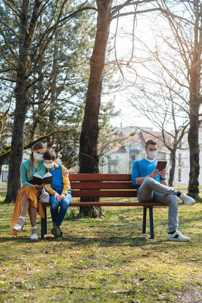 Люди, які сидять на лавці парку на сонці, практикують соціальне дистанціювання — стокове фото