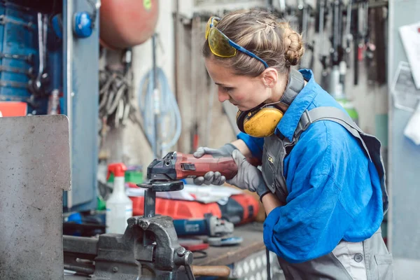 Žena mechanik pracuje s bruskou na disku — Stock fotografie