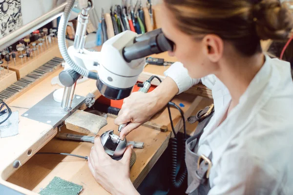 Fleißige Juwelierin arbeitet an ihrer Werkbank am Mikroskop — Stockfoto
