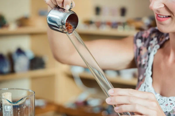 Woman putting red gemstones in a tube — Stock Photo, Image