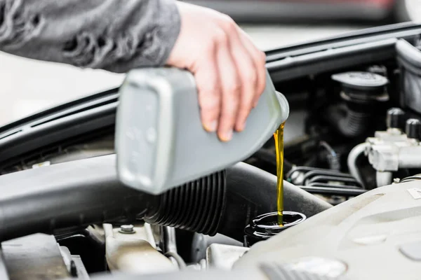 Woman putting oil into the engine of her car — Stock Photo, Image