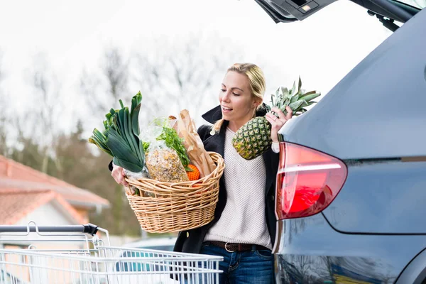 Mujer cargando comestibles después de comprar en el maletero de su coche —  Fotos de Stock