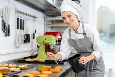 Pasta şefi küçük pastaları parlatıyor.