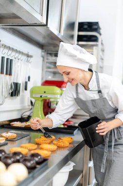 Pasta şefi küçük pastaları parlatıyor.