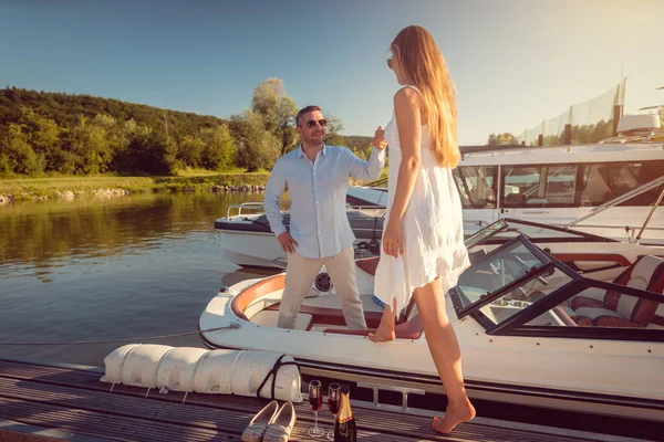 Man inviting a woman to his motorboot sitting in the river port — Stockfoto