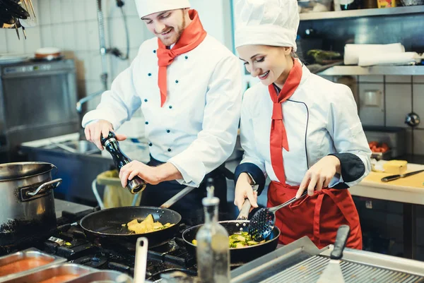 Equipo de chefs en una cocina preparando comida fantástica en sartenes —  Fotos de Stock