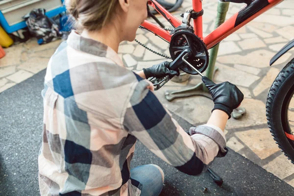 Mulher feliz trabalhando como mecânico de bicicletas — Fotografia de Stock