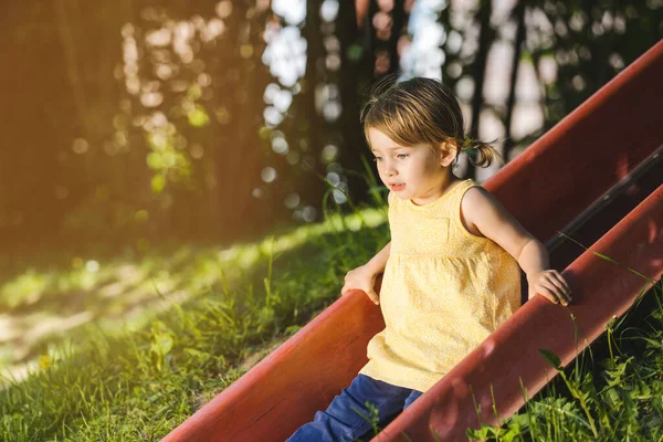 Mała dziewczynka na placu zabaw na szczycie zjeżdżalni — Zdjęcie stockowe