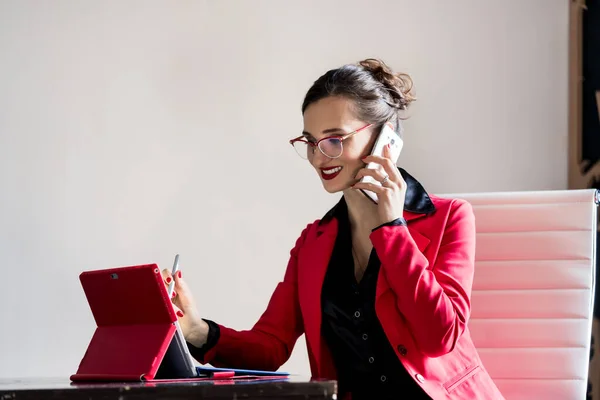 Forretningsdame som jobber med datamaskinen sin mens hun er i telefonen – stockfoto