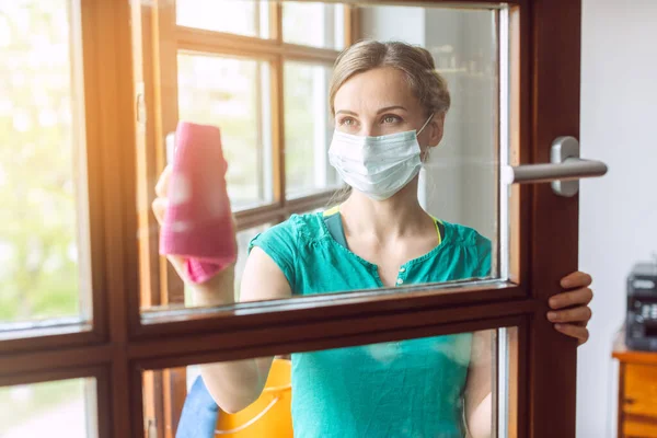 Frau putzt Fenster während Covid-19-Sperrung — Stockfoto