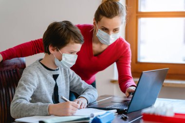 Anne ve oğlu maskeli öğretmenle görüntülü sohbet ediyor.