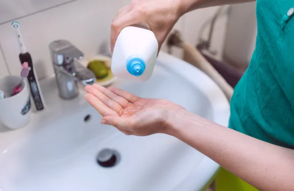 Vrouw desinfecteert haar handen in badkamer — Stockfoto