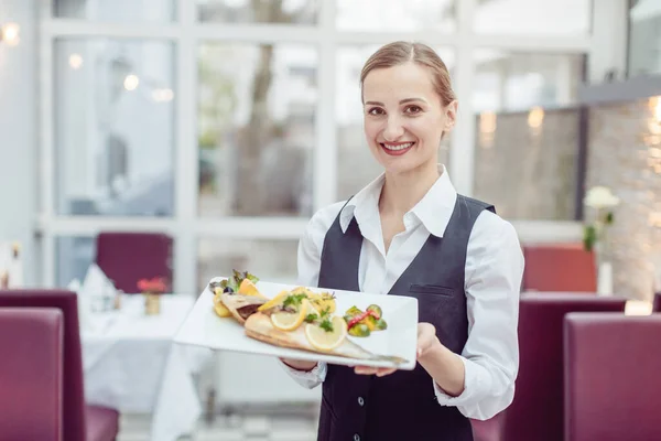 Camarera en un bonito restaurante presentando un sabroso plato — Foto de Stock