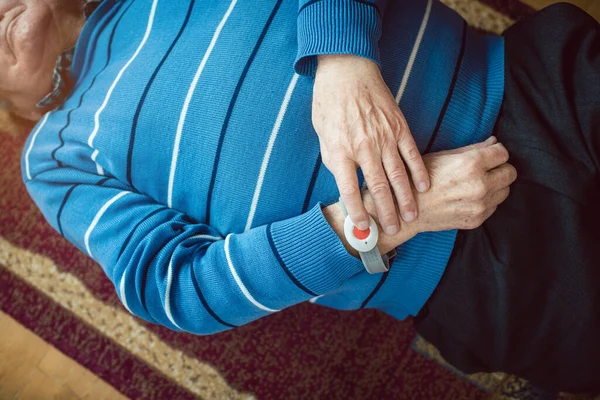 Hombre mayor caído pulsando el botón rojo en el dispositivo de llamada de emergencia —  Fotos de Stock