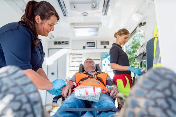 Emergency doctor in ambulance talking to injured man — Stock Photo, Image