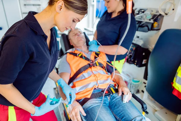 Médico de emergência dando injeção gota a homem ferido em ambulância — Fotografia de Stock